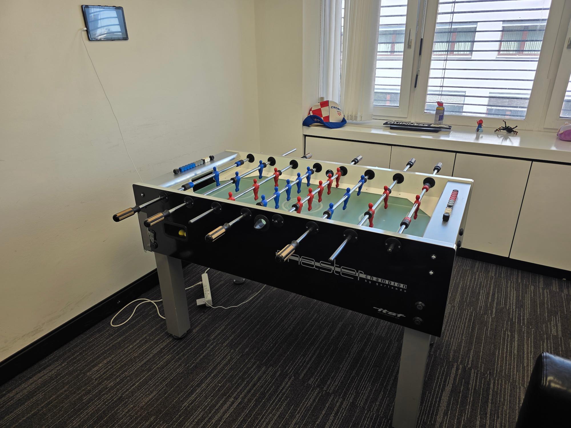 Image depicts a foosball table with a tablet mounted on the wall
and a Raspberry Pi setup mounted below the table.